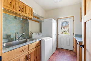 Laundry area with washer / dryer, cabinet space, and dark stone finish flooring
