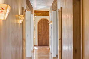 Hallway featuring arched walkways and light wood-style floors