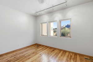 Spare room featuring rail lighting, light wood-style floors, and a textured ceiling