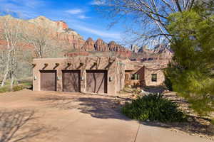 Pueblo-style home featuring a garage, concrete driveway, stucco siding, and a mountain view