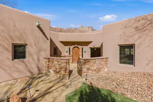 View of exterior entry with stucco siding and a patio area