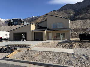 View of front of house with a mountain view, a garage, and a shingled roof