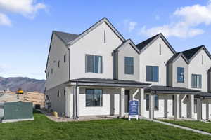 View of front of property with covered porch, a front yard, stucco siding, and a mountain view