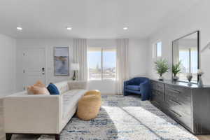 Living area with light wood finished floors and recessed lighting