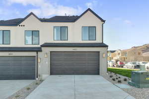 View of front of home with stucco siding, driveway, and a garage