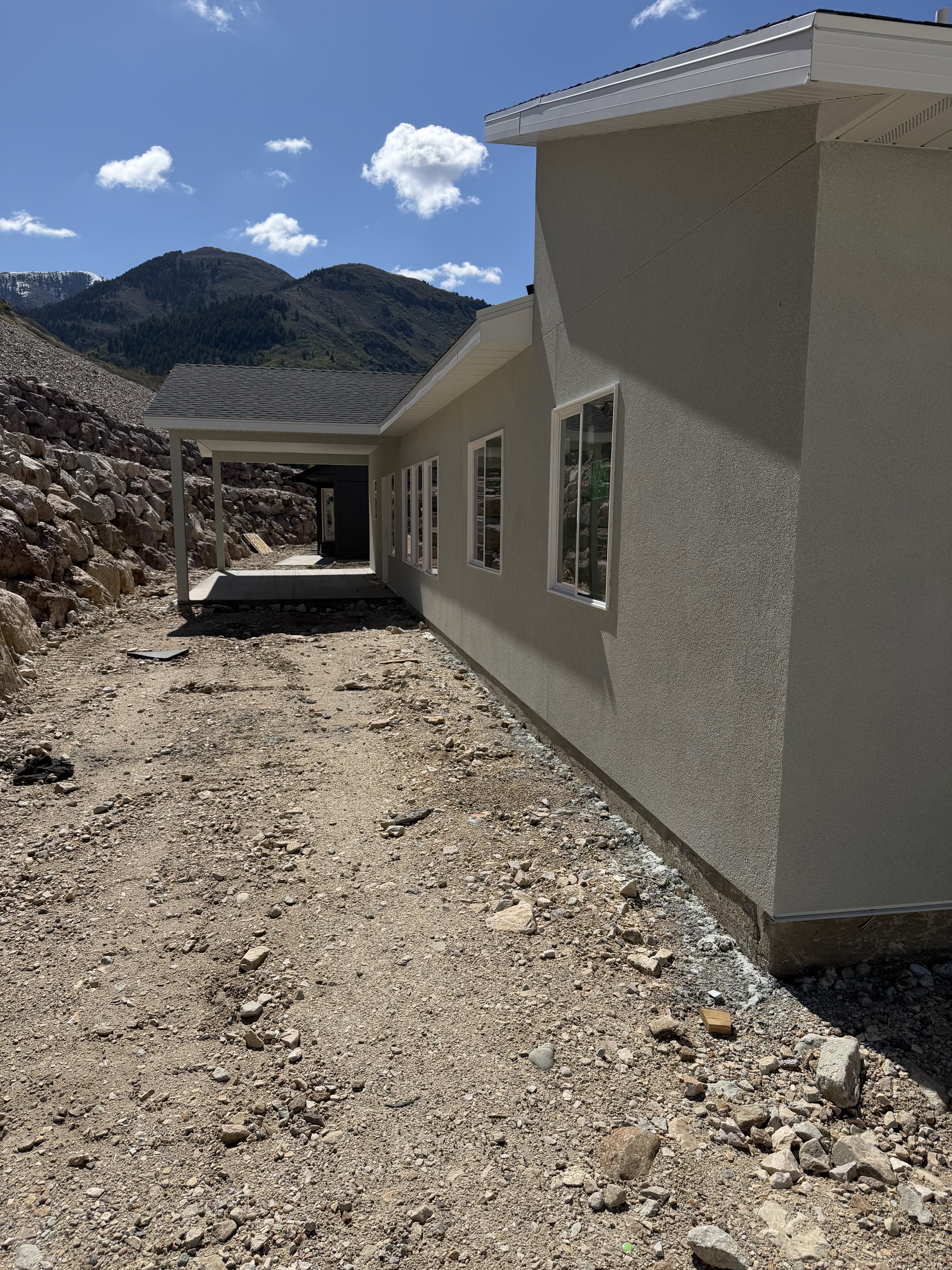 View of side of property with a mountain view, stucco siding, and a patio