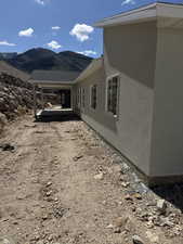 View of side of property with a mountain view, stucco siding, and a patio