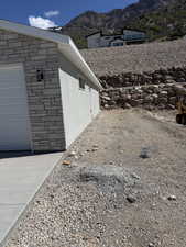 View of side of property with stone siding, a mountain view, and a garage