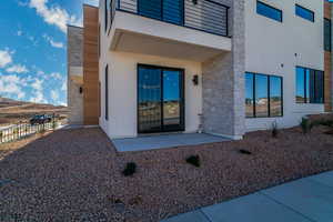 Entrance to property featuring stone siding, stucco siding, and a patio area