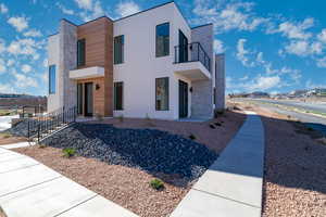 View of front of property with stone siding, stucco siding, a balcony, and a residential view
