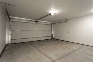 Garage featuring baseboards and a garage door opener