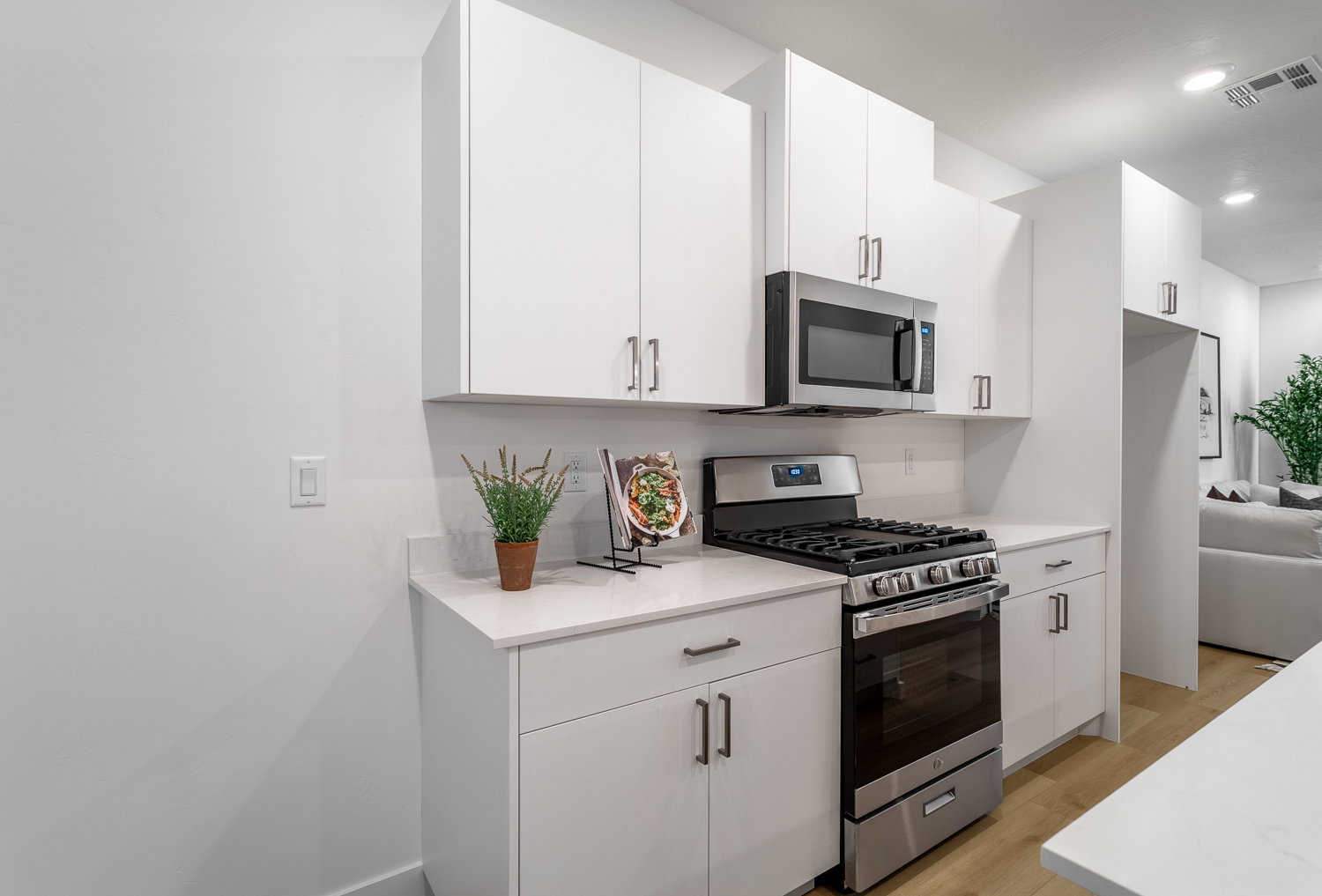 Kitchen featuring stainless steel appliances, white cabinets, light wood-style flooring, recessed lighting, and light stone counters