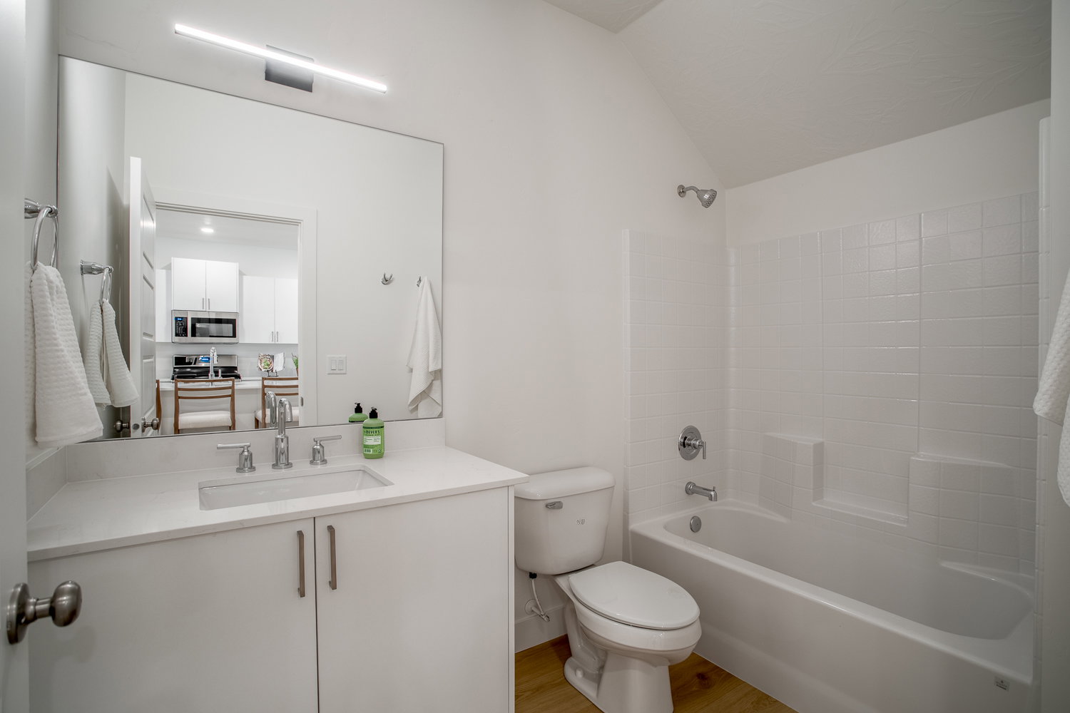 Bathroom with vanity, shower / washtub combination, light wood-style flooring, and lofted ceiling