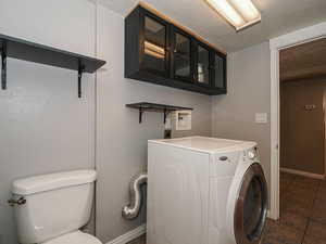 Laundry area featuring washer / dryer, a textured ceiling, and dark tile patterned floors