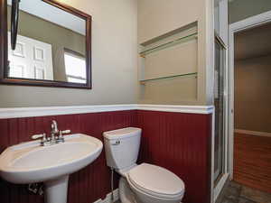 Full bath featuring wainscoting, stone finish flooring, and a shower stall