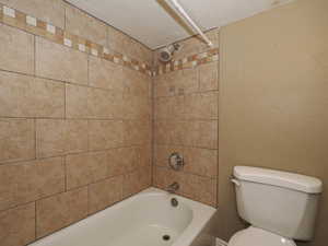 Bathroom with a textured wall, a textured ceiling, and shower / tub combination
