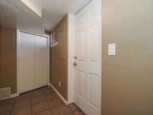 Entryway featuring a textured wall, tile patterned floors, and a textured ceiling