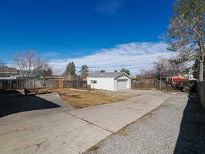Fenced yard featuring a garage, driveway, and an outdoor structure