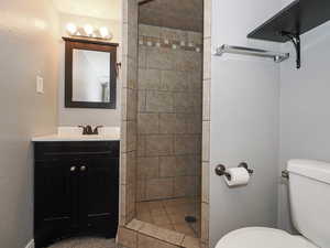 Full bathroom featuring vanity, a shower stall, and a textured wall