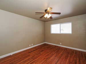 Spare room featuring dark wood-style flooring and a ceiling fan