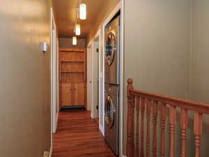 Laundry area with dark wood-style floors and stacked washer and dryer