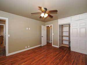 Unfurnished bedroom featuring dark wood-style floors, a closet, and ceiling fan