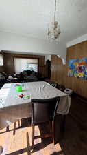 Dining space with wood walls, a textured ceiling, wood finished floors, a chandelier, and arched walkways