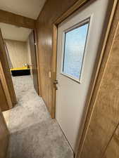 Hall featuring light colored carpet and wood walls