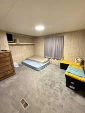 Carpeted bedroom with a closet and wood walls