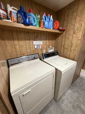 Laundry area with light carpet, washer and clothes dryer, and wooden walls