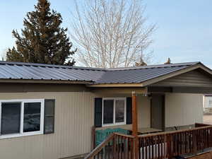 View of property exterior with a wooden deck and a metal roof