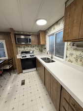 Kitchen with wood finish cabinets, gas range oven, light countertops, stainless steel microwave, and light flooring