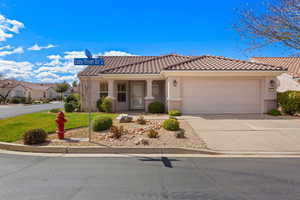 Mediterranean / spanish-style house featuring driveway, a garage, covered porch, a tiled roof, and a front yard