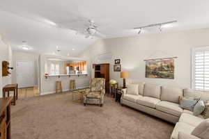 Living room with rail lighting, ceiling fan, carpet flooring, and lofted ceiling