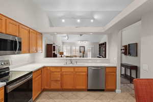 Kitchen with stainless steel appliances, light countertops, vaulted ceiling, open floor plan, and rail lighting