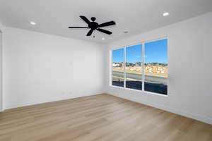Empty room with ceiling fan, light wood finished floors, and recessed lighting
