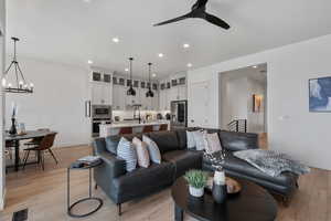 Living area with a ceiling fan, light wood finished floors, and suspended lighting