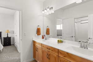 Bathroom with double vanity, light carpet, and a shower with shower curtain