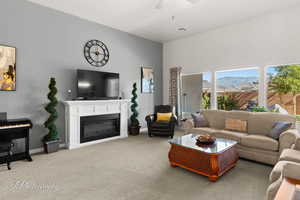 Carpeted living room with a glass covered fireplace and ceiling fan