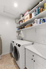 Laundry room with washer and dryer, cabinet space, and light tile patterned flooring