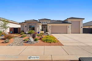 Prairie-style home featuring an attached garage, stucco siding, driveway, a tile roof, and stone siding