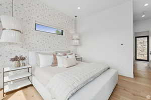 Bedroom featuring light wood-style floors, wallpapered walls, and recessed lighting