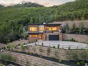 View of front of house featuring concrete driveway, an attached garage, a chimney, and a patio
