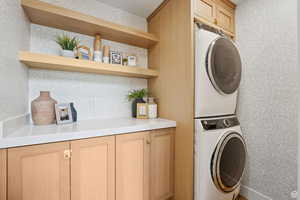 Laundry room with stacked washer and clothes dryer and cabinet space