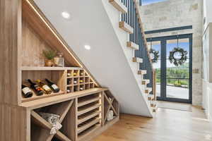 Wine area with plenty of natural light, light wood-style floors, and a high ceiling