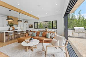 Living area with recessed lighting, beam ceiling, and light wood-style flooring