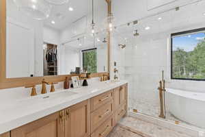 Bathroom featuring double vanity, a spacious closet, a freestanding tub, and a stall shower