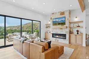 Living room with light wood-style flooring, a fireplace, recessed lighting, and beam ceiling