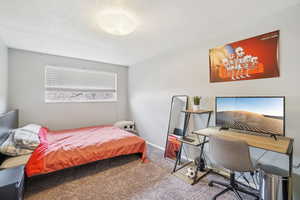 Bedroom featuring carpet, an office area, and a textured ceiling
