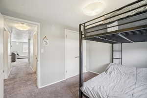 Carpeted bedroom with baseboards and a textured ceiling